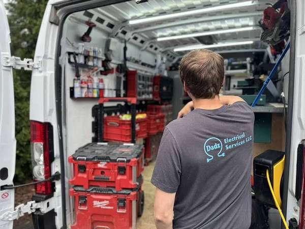 Electrician unloading supplies from a service van at a home